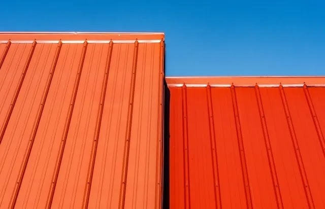 A metal roof with vibrant red panels, illustrating the sleek, durable appearance of metal roofing compared to the more traditional asphalt shingles.