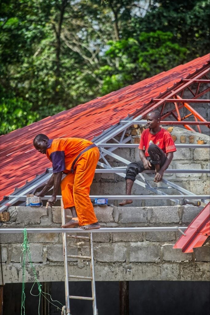 Roofing workers installing and securing metal roofing panels, illustrating professional techniques used to repair leaks and restore roof durability.

