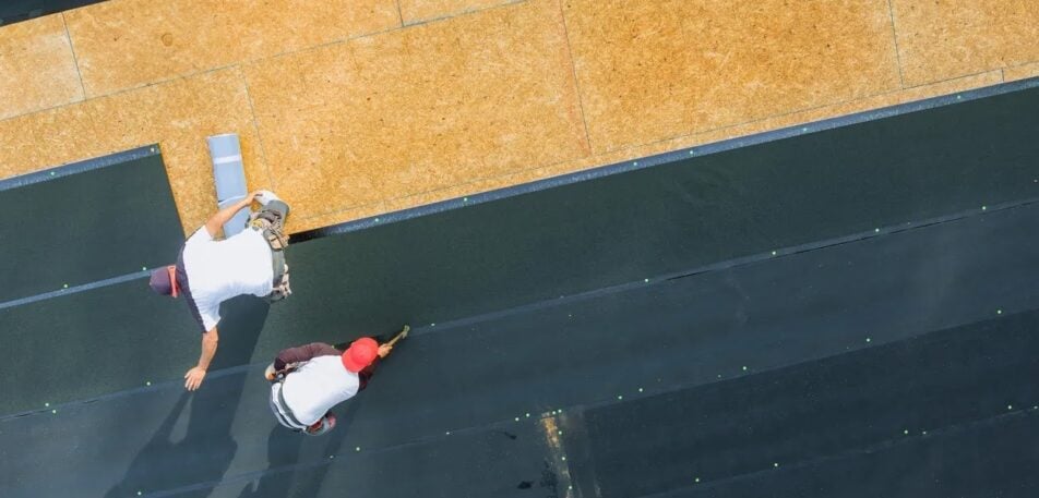 Roofing professionals installing durable roofing materials on a residential roof, demonstrating construction techniques designed to withstand extreme weather conditions.
