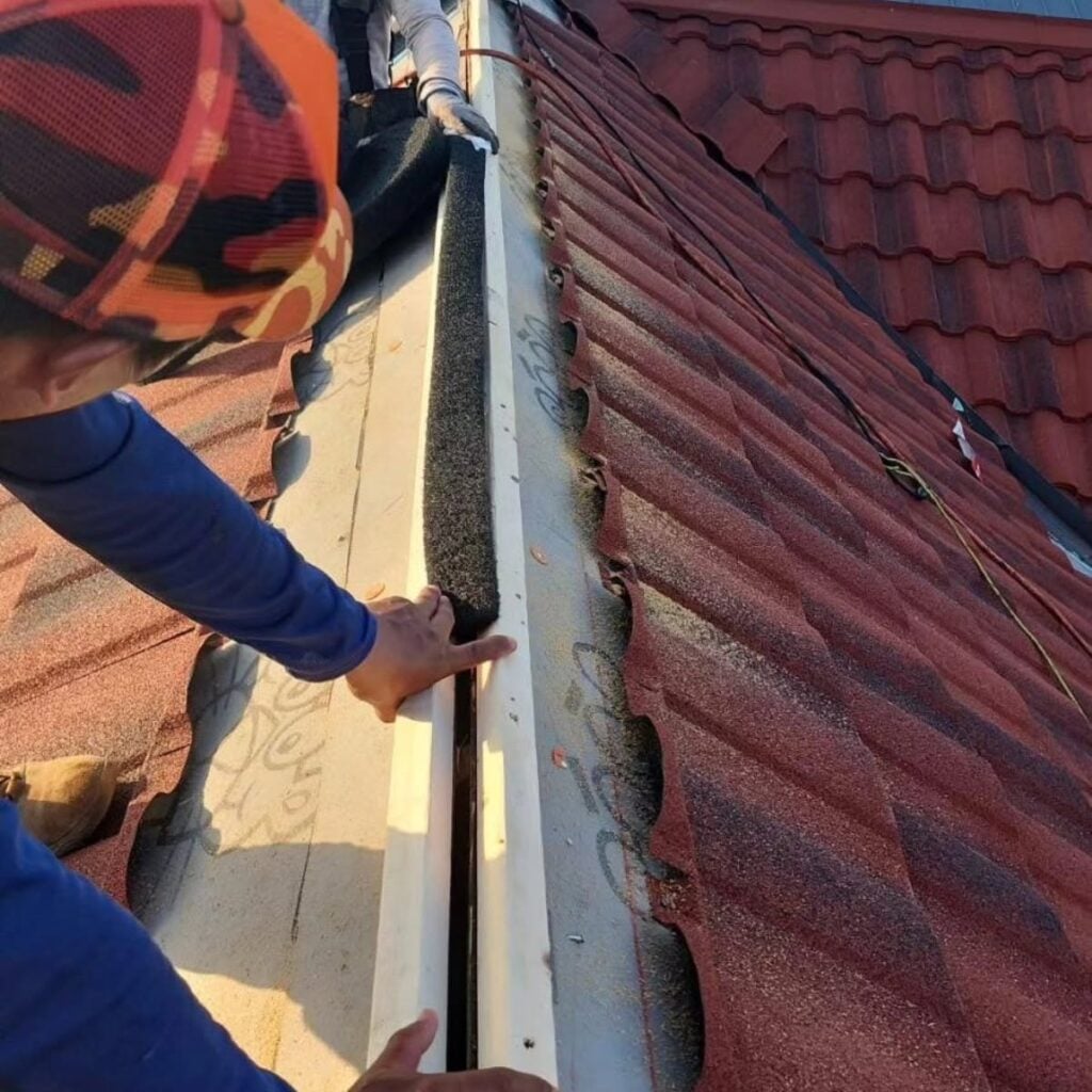 Technician inspecting and maintaining rooftop shingles on a residential home
